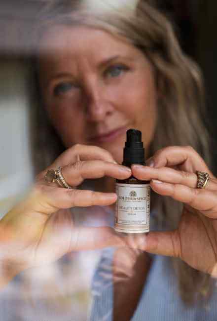 Natascha Koningsveld founder holistic beautymerk Colour@Spice natuurlijke huidverzorging toont een flesje Beauty Detox gezichtsserum 