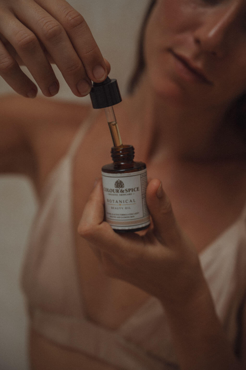 vrouw met pipet met botanical beauty oil van Colour and Spice in bruin glazen flesje etiket holistic skincare natuurlijke huidverzorging