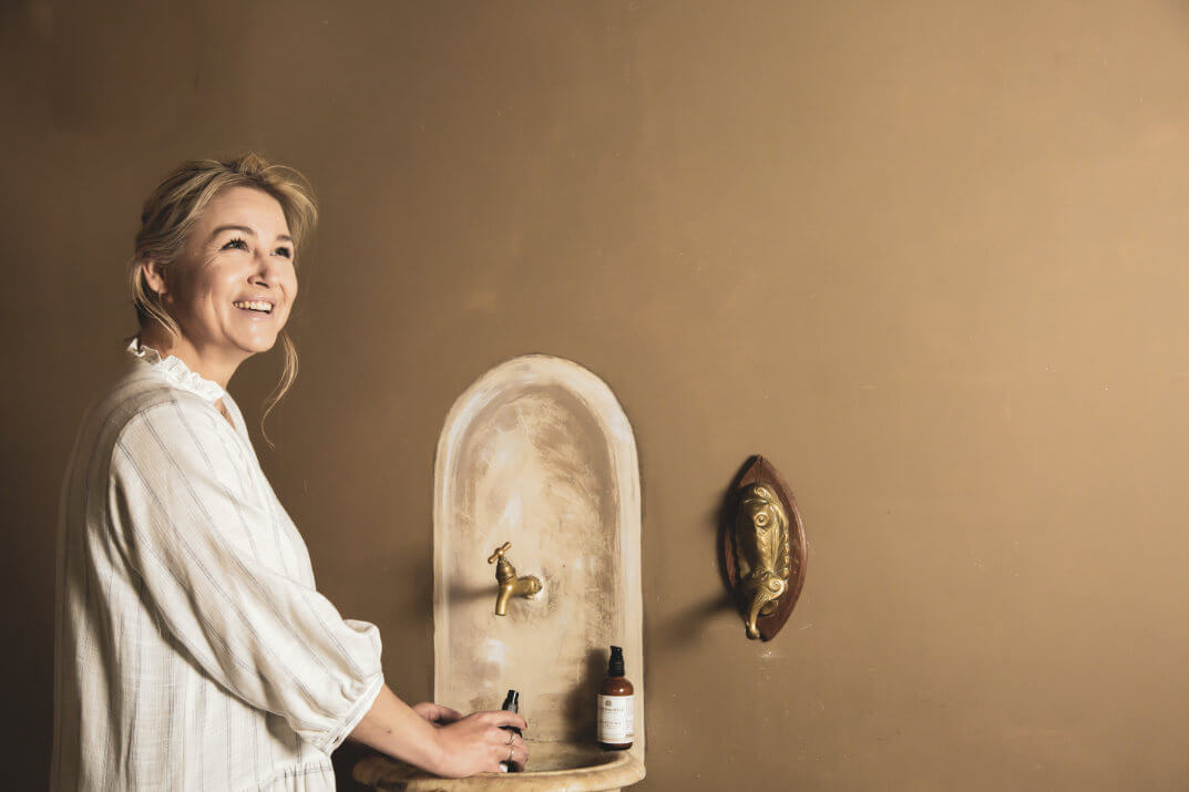 Vrouw die toekomst voor zich ziet staand aan fontein met producten natuurlijke huidverzorging, naturel 